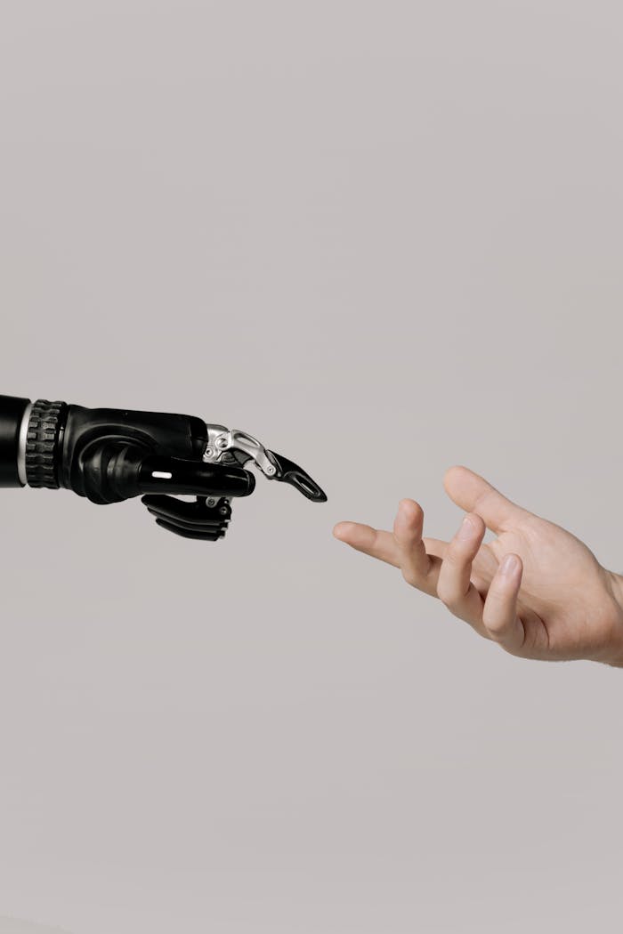 our-story A human hand reaching to touch a bionic prosthetic hand on a white background.